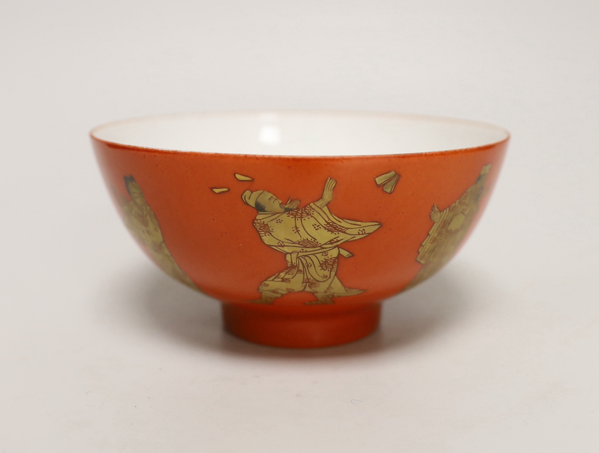 A Chinese coral red ground bowl, gilded with figures, 14cm diameter